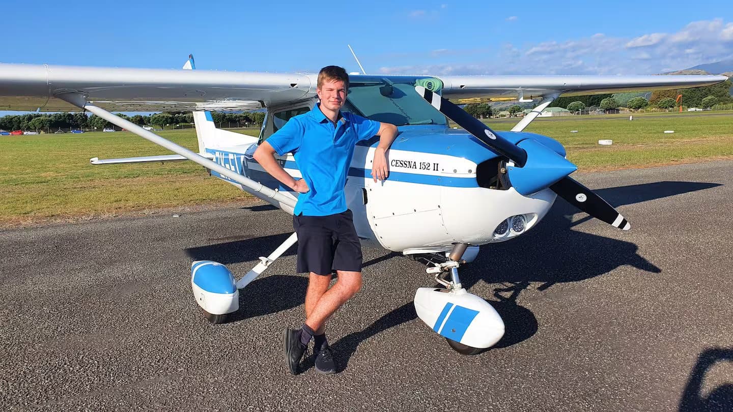 Hamish standing beside a Cessna 152 on the airfield after his first solo flight