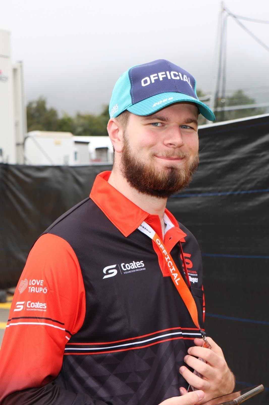 Hamish smiling, wearing a Supercars volunteer officials shirt and cap